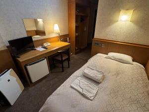 a hotel room with a bed and a desk with a computer at Ohta Grand Hotel in Ota