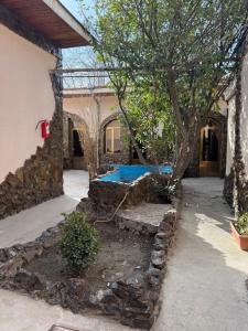 a house with a tree and a stone wall at Dom Hostel in Samarkand