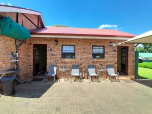 a patio with chairs and a table and a building at Meerkat Manor on Main in Clarens