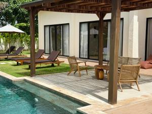 a patio with chairs and a swimming pool at Villa YAOUH à Seseh in Munggu