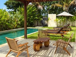 a patio with chairs and a table and a pool at Villa YAOUH à Seseh in Munggu