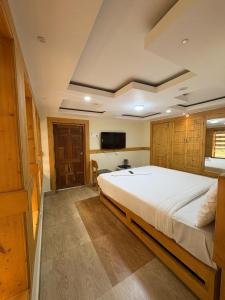 a bedroom with a large bed and a flat screen tv at Rozana Retreats Ooty in Ooty