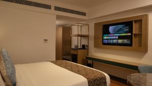a hotel room with a bed and a flat screen tv at Coral Reef Kakkanad in Cochin