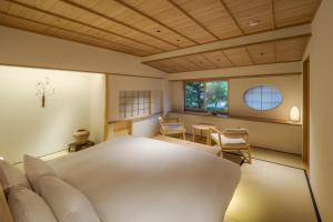 a bedroom with a white bed and a table and chairs at 季楽 邸 清水 Kiraku Tei Kiyomizu in Kyoto