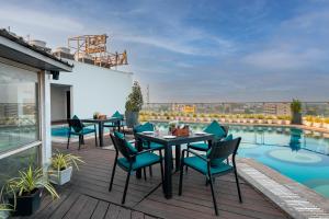 a balcony with tables and chairs and a swimming pool at Pal Heights Mantra in Bhubaneshwar