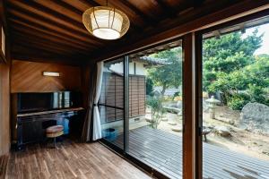 a screened in porch with a sliding glass door and a microwave at ゲストハウス nagatafure in Iki