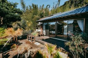 a house with a wooden deck in the garden at ゲストハウス nagatafure in Iki