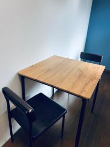 a wooden table with two black chairs and a table and a table and two chairs at 宿えんがわーおもや in Tokorozawa