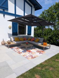 a couch under an umbrella on a patio at Fleurs in Bassussarry