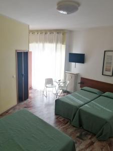 a bedroom with two green beds and a table at Pensione Aurora in Imperia