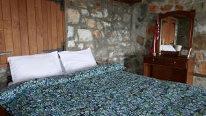 a bedroom with a bed and a stone wall at Studio in Elatochori - O Elato in Elatochori