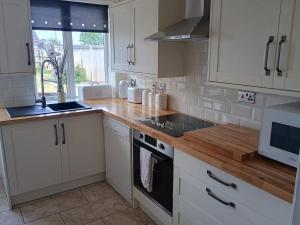 a kitchen with white cabinets and a wooden counter top at Bideawee in Belton