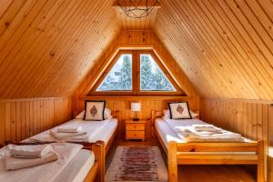 two beds in a wooden room with a window at Chata Groń in Groń