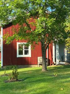 a red building with a bench next to a tree at Lillhuset Gallerud in Årjäng