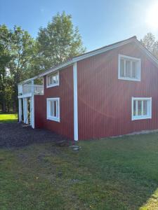 a red barn with white windows on the side of it at Lillhuset Gallerud in Årjäng +10 photos