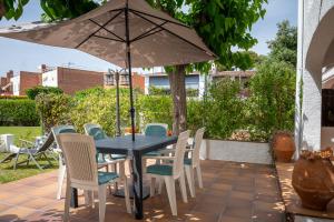 a table and chairs with an umbrella on a patio at AT084 Piscina compartida con 3 casas y vistas al mar in Torredembarra