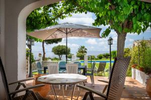 a table and chairs with an umbrella on a patio at AT084 Piscina compartida con 3 casas y vistas al mar in Torredembarra