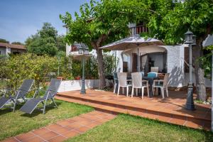 a patio with a table and chairs and an umbrella at AT084 Piscina compartida con 3 casas y vistas al mar in Torredembarra