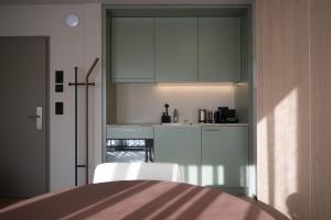 a kitchen with white cabinets and a table and chairs at Stadtloft Suites Cham-Zug in Cham