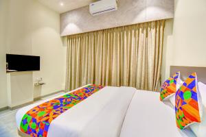 a bedroom with a white bed with a colorful blanket at FabHotel Chhappan in Aurangabad +35 photos