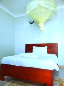 a bedroom with a bed with a lamp on the wall at Kanti Guest House, Arua in Arua +3 photos