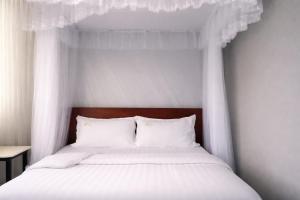 a bed with a canopy with white sheets and pillows at Kanti Guest House, Arua in Arua