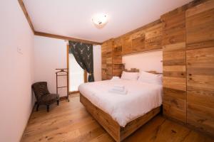 a bedroom with a bed with a wooden wall at Arga' New Alpine Design Apartment Central & Scenic Views in San Vito di Cadore