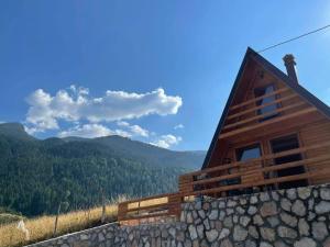 a log cabin with a stone wall next to a mountain at Villat Loni in Peje