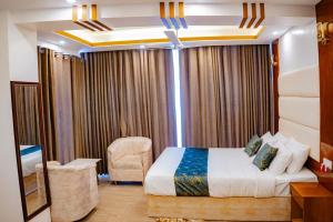 a bedroom with a bed and a chair in a room at The Elegance Hotel & Suites in Chittagong