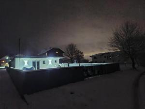 a white house with a fence in the snow at night at Apartment Lane in Bihać