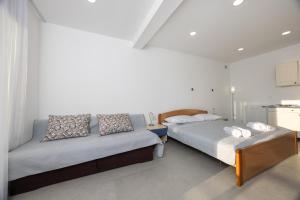 two beds in a room with white walls at Apartments Klaricic in Živogošće