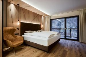 a bedroom with a bed and a chair and a window at VALARA Alpine Art Hotel in Tux +70 photos