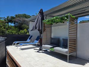 a patio with two chairs and an umbrella at La Petite Case Tomi in Saint-Louis