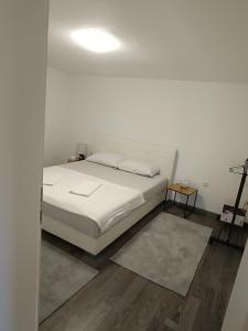 a white bedroom with a bed and a lamp at Apartment Lane in Bihać +8 photos