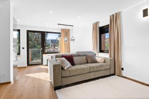 a living room with a couch and some windows at Apartmány La Torretta in Harrachov
