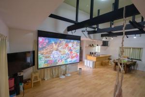 a large projection screen in a room with a table at 里山ハウス in Kamogawa