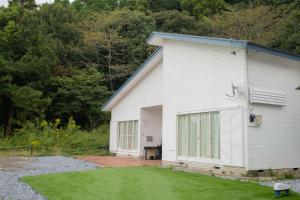a white house with a lawn in front of it at 里山ハウス in Kamogawa