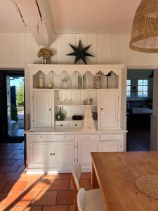 a kitchen with white cabinets and a dining table at Maison OHANZIA Villefranque in Villefranque