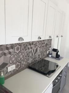 a kitchen with white cabinets and a tile back splash at Casa Andrean PT Lido Venezia in Venice-Lido