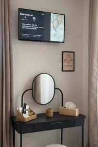 a table with a mirror and a tv on a wall at La Villa Blanche Appart hôtel in Salles