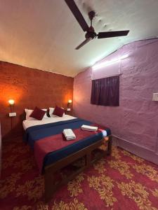 a bedroom with a bed and a ceiling fan at Prakriti Resort in Arambol