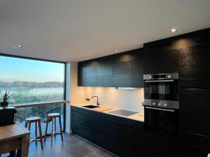 a kitchen with black cabinets and a large window at Huisje Scheldevallei in Temse