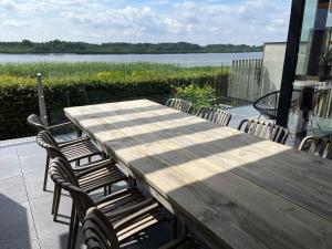 a wooden table and chairs on a patio with a lake at Huisje Scheldevallei in Temse
