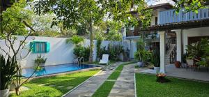 a backyard with a swimming pool next to a house at Surf Villa Hikkaduwa in Hikkaduwa