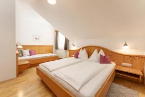 a bedroom with a large white bed with purple pillows at Kainreiterhof in Aich