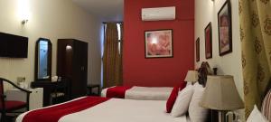 a hotel room with two beds and a red wall at Herfa INN Hotel Lahore in Lahore