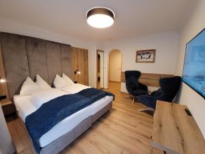 ein Hotelzimmer mit Bett, Schreibtisch und Stühlen in der Unterkunft Hotel Sommerer - Hike & Bike in Saalbach, Joker Card inkl in Saalbach-Hinterglemm