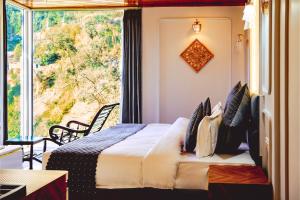 a bedroom with a bed and a large window at Sunoraa Luxury Hotel & Spa in Mussoorie +23 photos