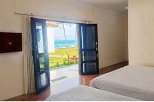 a bedroom with a door with a view of the ocean at La Plage Beach Club in Tjikakaka +20 photos