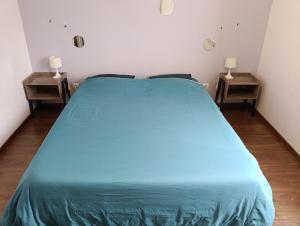 a bedroom with a blue bed with two night stands at Hébergements Sylvain in Neuilly-lʼÉvêque